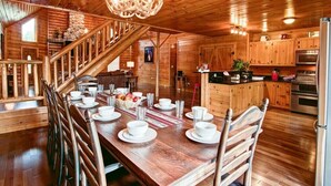 Ein Holzhütten-Innenraum mit Essbereich, Küche und Treppe.