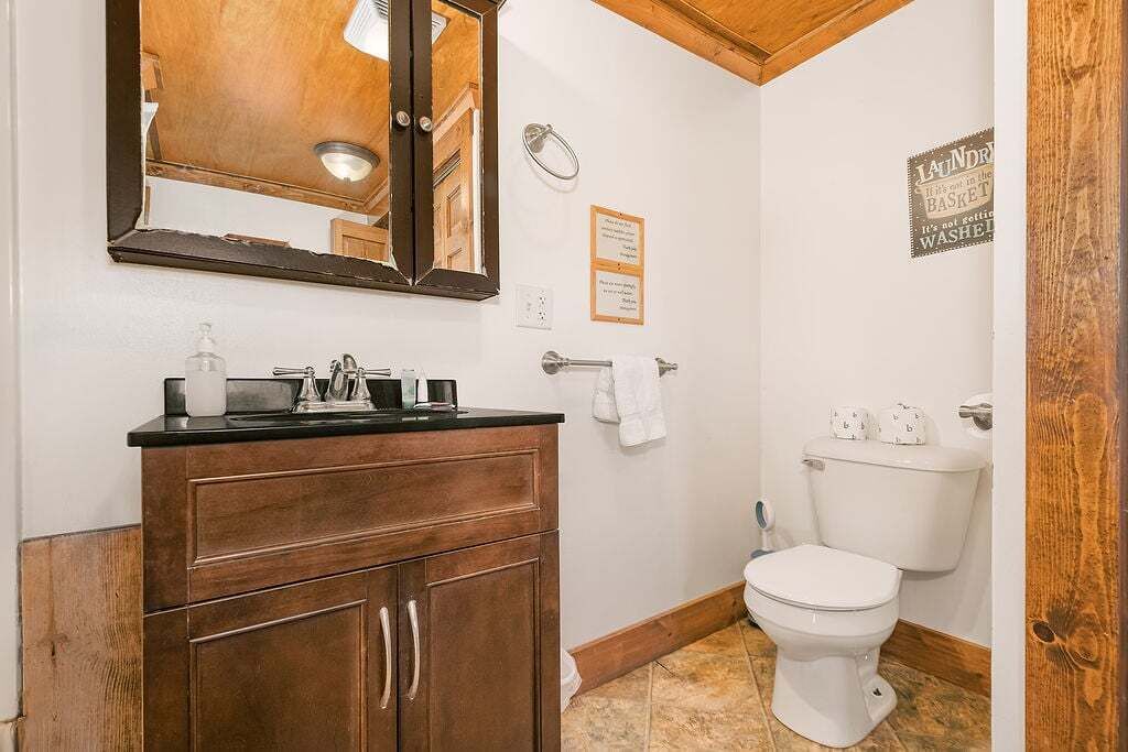 A bathroom with a wooden vanity, a mirror, a toilet, and a hand dryer.