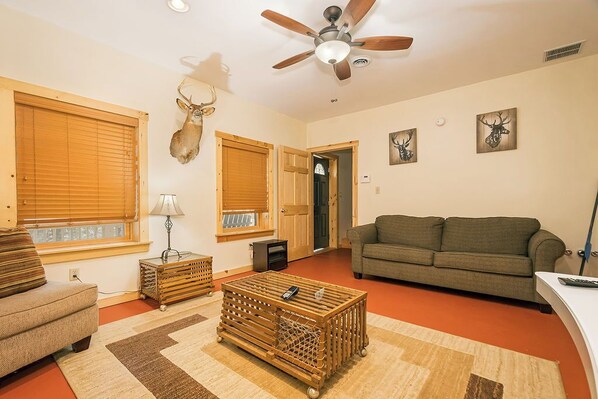 Una sala de estar con ventilador de techo, sofá, mesa de centro y chimenea.