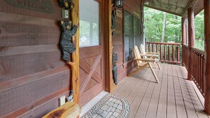 Eine Holzhütte mit Veranda, einer Willkommensschild und Bär-Dekorationen.