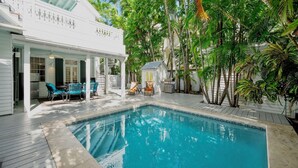 Un espace piscine doté d’un patio couvert, de coins salon extérieurs et d’une végétation luxuriante.