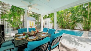 Un espace extérieur aménagé pour les repas, avec une piscine, le tout entouré d’une végétation luxuriante.