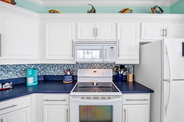 A kitchen with white cabinets, a blue countertop, a white stove, a microwave, and a refrigerator. - Penthouse in Paradise Gulf with a magnificent view! (Orange Beach)
