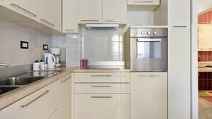 Una cocina moderna con armarios blancos, electrodomésticos de acero inoxidable y un salpicadero de azulejos.