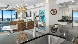 Una cocina moderna con una isla grande, pileta de acero inoxidable e iluminación colgante.