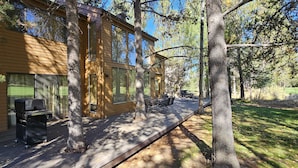 Une maison en bois avec un patio, un espace salon extérieur et un barbecue.