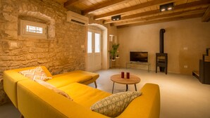 A cozy living room with a stone wall, wooden beams, a fireplace, and a TV. - Casa Sepia in Trogir old town for up to 6 people (Trogir)