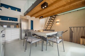Una cucina moderna con zona pranzo, caratterizzata da una scala a chiocciola, mobili bianchi e un tavolo apparecchiato per quattro persone.