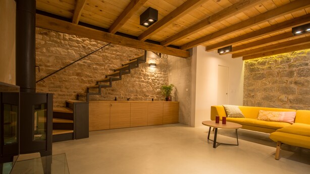 A modern living room with a stone wall, wooden staircase, and a yellow sofa. - Casa Sepia in Trogir old town for up to 6 people (Trogir)