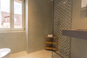 Une salle de bain comprenant des toilettes, un espace douche et un meuble-lavabo avec un miroir.