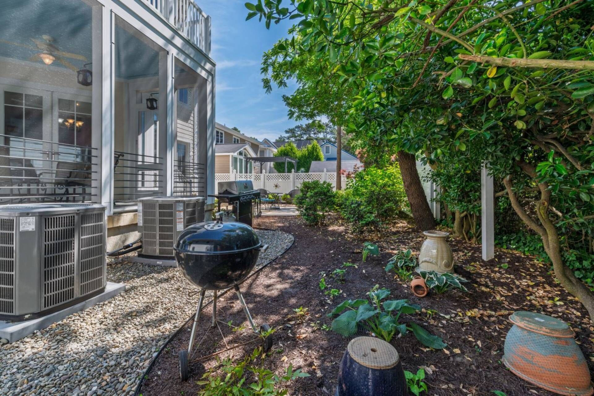 A residential area with a house, outdoor grill, and garden.