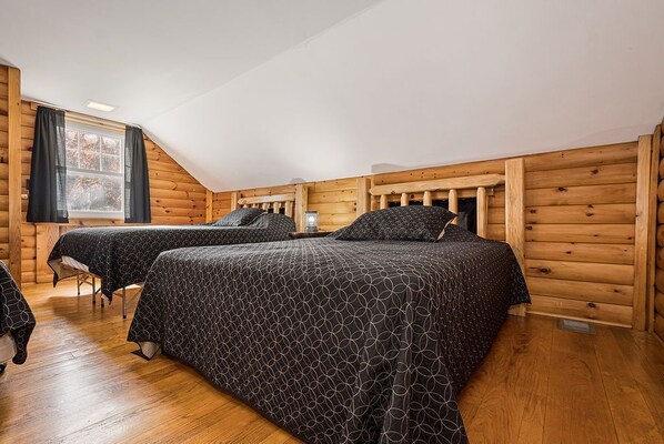 A log cabin bedroom with two beds, a window, and wooden walls. - Cedar Lodge - Rustic Lodge Escape for Friends & Family (Farmington)