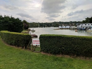 A lakeside view with boats, a sign warning of deep water, and a row of houses along the shore.