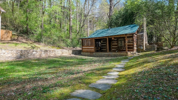 Ein rustikales Blockhaus mit Steinuntergrund und Holzfassade, umgeben von einer Steinmauer und einem Steinweg, der dorthin führt.
