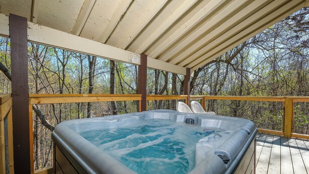 A hot tub on a wooden deck with a view of trees. - 5BR in Gatlinburg with hot tub and pool table! 1 free ticket to Dollywood! (Gatlinburg)