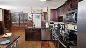 A kitchen with dark wooden cabinets, stainless steel appliances, and a central island. - 5BR in Gatlinburg with hot tub and pool table! 1 free ticket to Dollywood! (Gatlinburg)