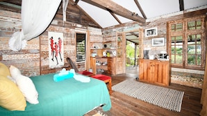 A rustic wooden cabin with a bed, a small kitchen area, and a dining table. - Le Cabanon, perfect for nature lovers (Le Morne)
