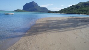 A beach with clear turquoise water, a boat, and a mountain in the background. - Le Cabanon, perfect for nature lovers (Le Morne)