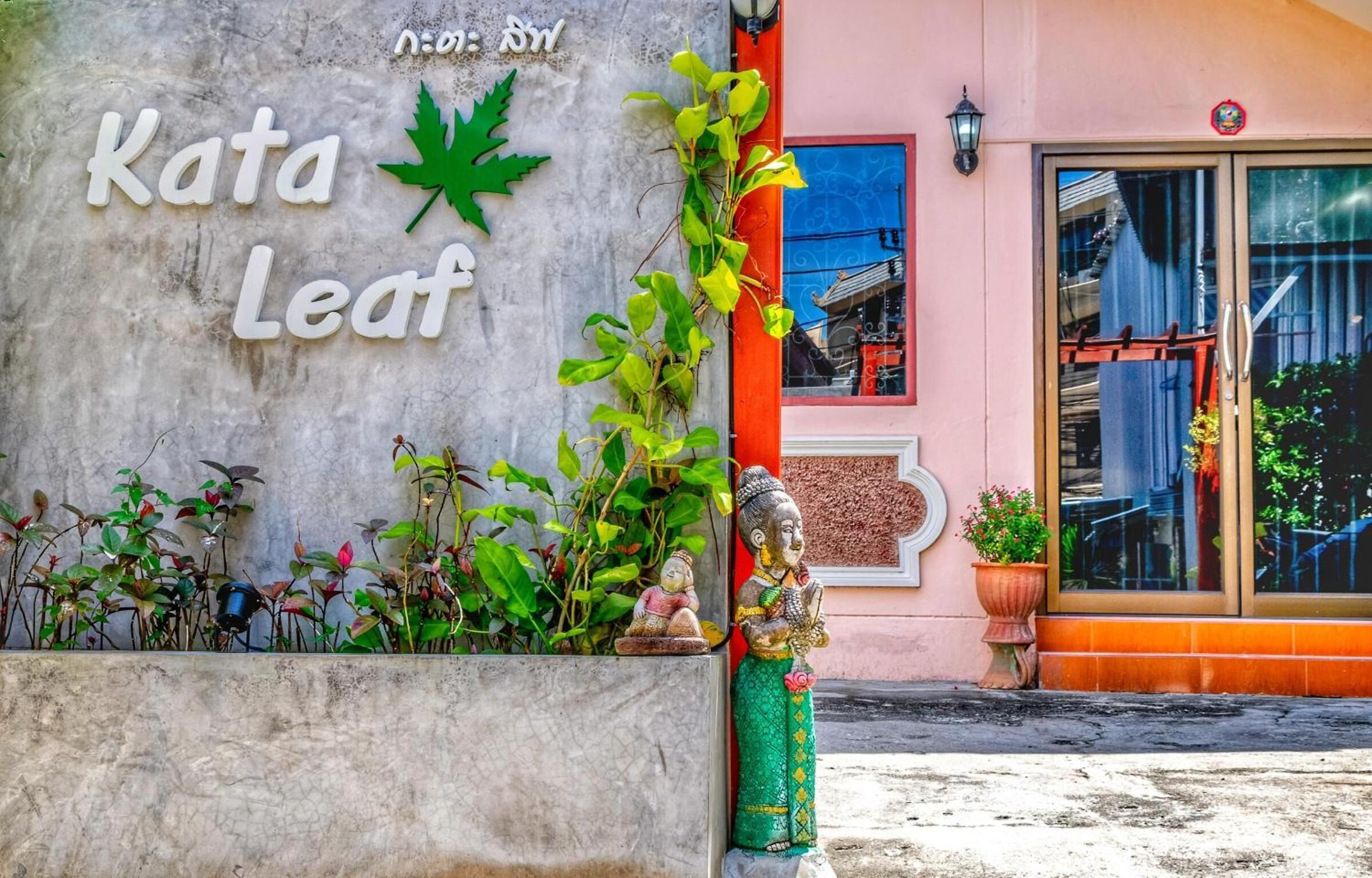 Un edificio con un cartel que dice "Kata Leaf" y una estatua decorativa.