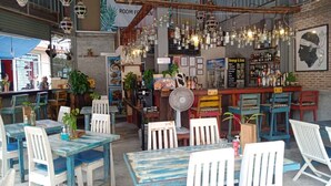A cozy restaurant with rustic decor, wooden tables and chairs, hanging light fixtures, and a bar area with various bottles. - Kata Leaf Resort (Karon)