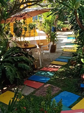 A patio area with a table and chairs, surrounded by potted plants and a colorful pathway. - Kata Leaf Resort (Karon)
