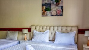 A hotel room with two beds, white linens, a tufted headboard, and a wall-mounted artwork. - Kata Leaf Resort (Karon)