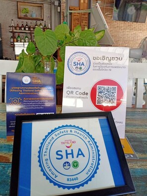 A framed certificate from the Thailand Safety & Health Administration (SHA) with a QR code and a signboard with Thai text. - Kata Leaf Resort (Karon)