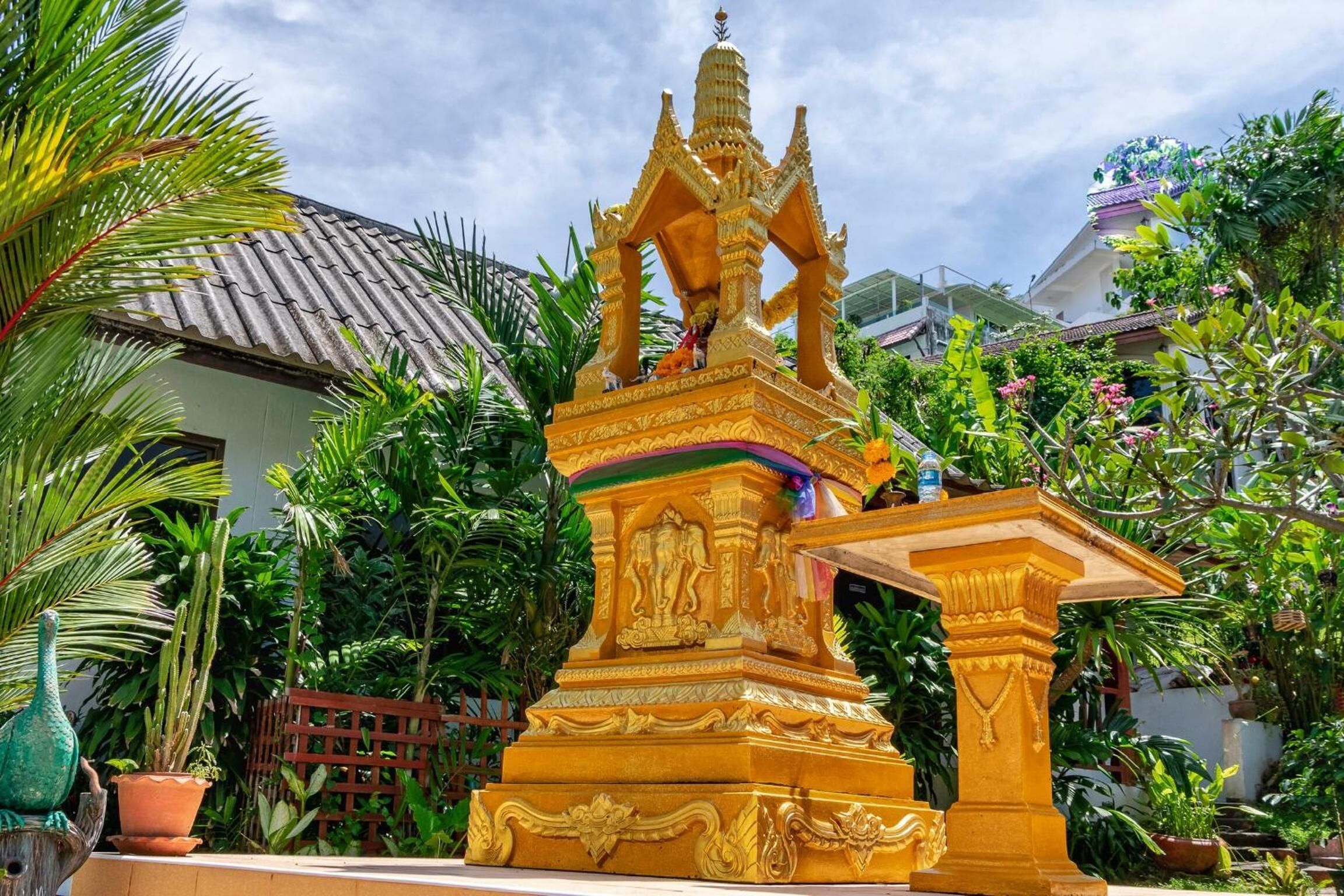 Una estatua dorada con detalles tallados en un jardín.