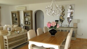 A dining room with a wooden table, white chairs, and a vase of flowers. - Lirios Boutique Luxury Seaview Villa ⭐︎⭐︎⭐︎⭐︎⭐︎ (Benitachell)