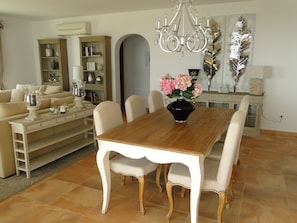 A dining room with a wooden table, white chairs, and a vase of flowers.
