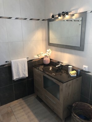 Ein modernes Badezimmer mit einem Holzlagerfläschchen, einem großen Spiegel und einem Handtuchhalter.