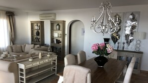 A modern living room with a sofa, dining table, and decorative items. - Lirios Boutique Luxury Seaview Villa ⭐︎⭐︎⭐︎⭐︎⭐︎ (Benitachell)