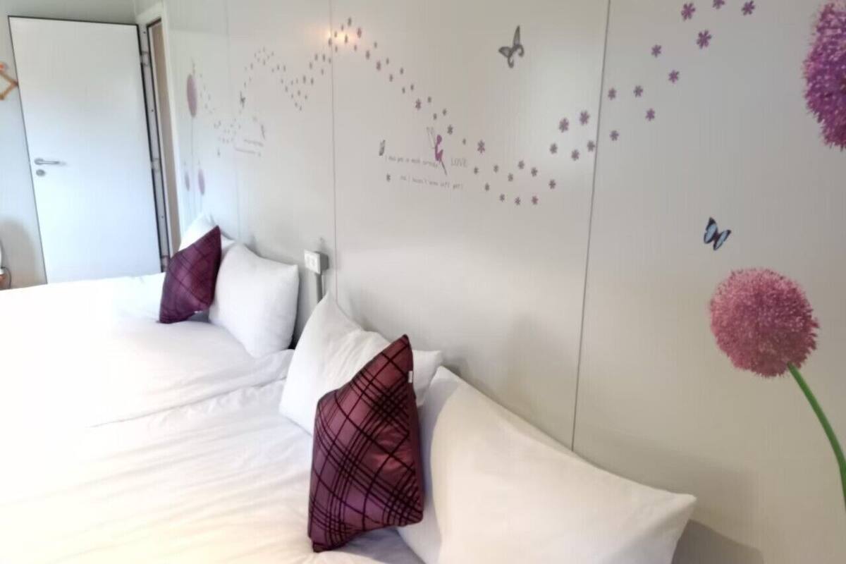 A hotel room with a large bed, white bedding, and decorative wall art including flowers and butterflies.