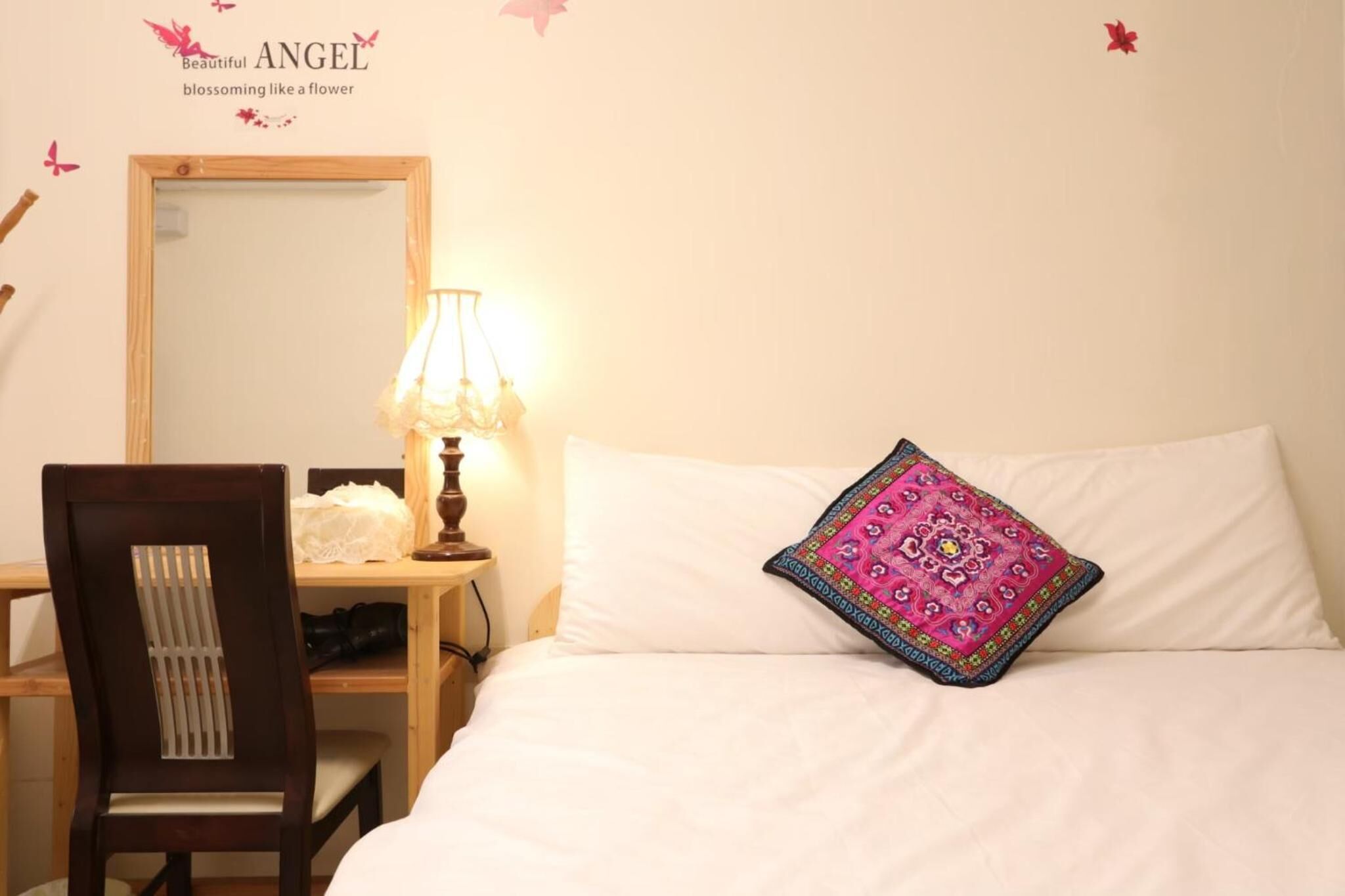 A bedroom with a bed, a chair, a desk, a lamp, and a mirror.
