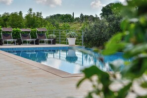 Una piscina con sillas de descanso y una planta en maceta.