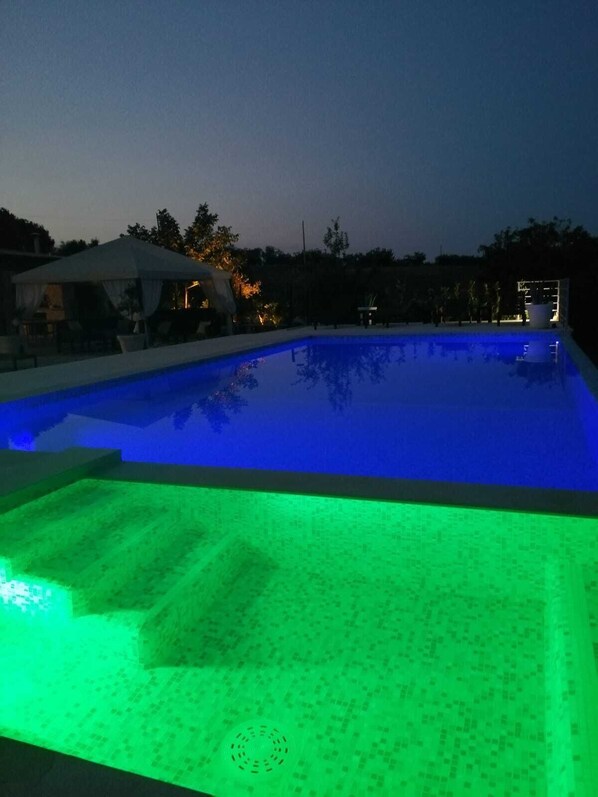 A swimming pool at dusk with a blue and green illuminated edge. - Villa (Casa Sergio) with a private pool and hot tub (Monopoli)