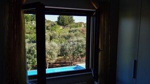Ein Zimmer mit Blick auf einen Pool und einen bewaldeten Bereich.