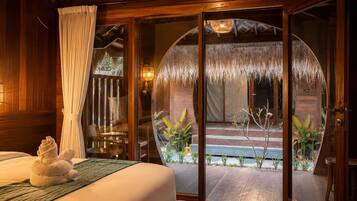 A room with a bed, a large window with a view, and a wooden ceiling.