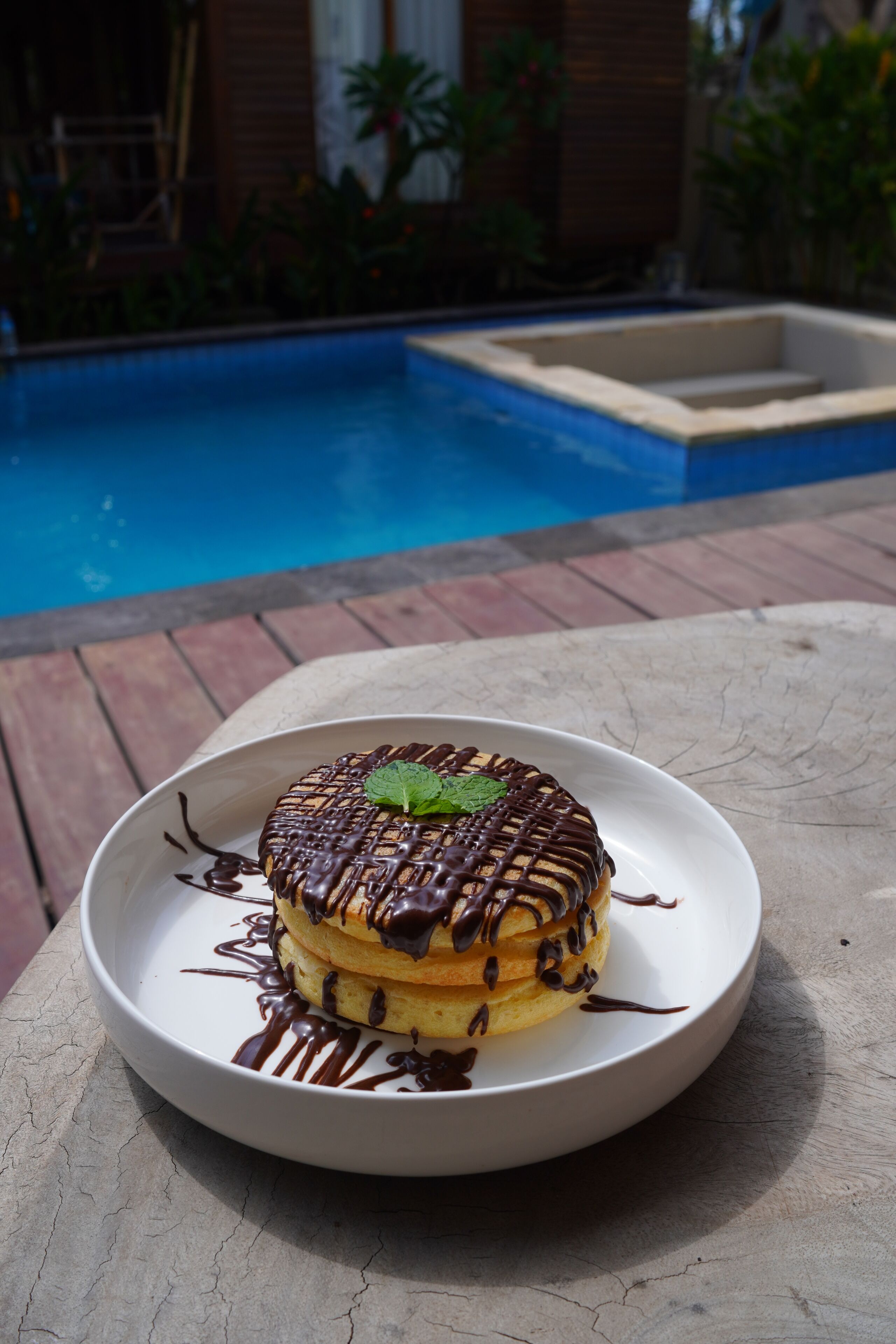 A dessert on a plate with a pool in the background.