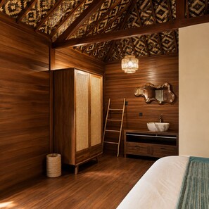 A room with wooden walls, a bed, a wardrobe, a mirror, and a chandelier. - Sadev Resort (Gili Trawangan)