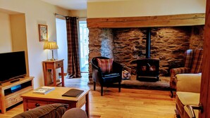 A cozy living room with a stone wall, a fireplace, a television, and comfortable seating.
