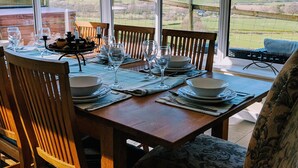 A dining area with a table set for four, large windows offering a view of the countryside.