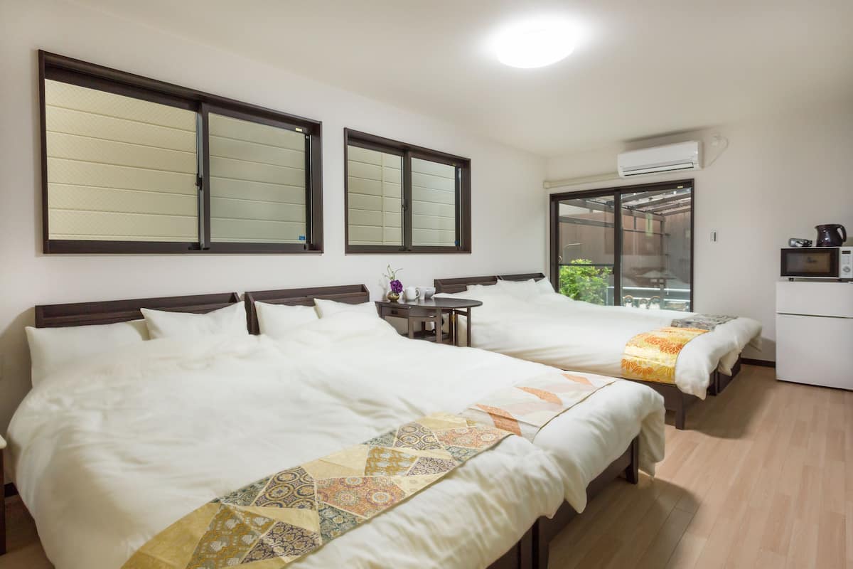 Una camera d'albergo con due letti, un piccolo tavolo, un forno a microonde e un condizionatore d'aria.