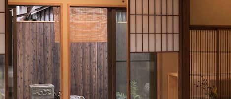 A traditional Japanese room with tatami flooring, a sliding shoji screen door, a stone lantern, and a bed with a red and white bedding.