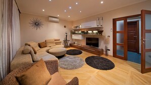 Un soggiorno moderno con un divano componibile, una TV a schermo piatto e un pavimento in legno.
