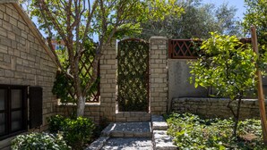 Un vialetto in pietra conduce a un cancello chiuso, circondato dal verde e da un edificio in mattoni.