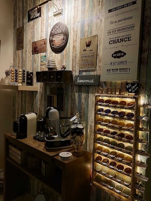 A coffee shop interior with a coffee machine, a display of coffee cups, and various signs on the wall.