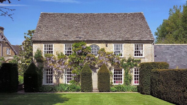 A stone building with a symmetrical facade, multiple windows, and a central arched window.