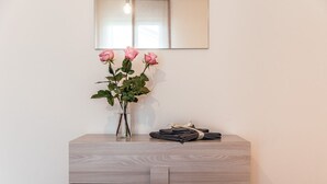 A wooden dresser with a vase of pink roses and folded towels. - Apartment in Giavera del Montello for up to 4 people (Giavera del Montello)