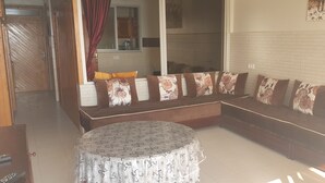 Una sala de estar con un sofá, una mesa redonda y una cocina visible a través de una puerta abierta.